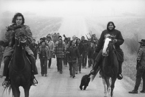 Harlington Wood, Assistant U.S. Attorney General, third row center without hat, is escorted into the village of Wounded Knee by militant Indians of the AIM group, March 13, 1973. Second row, left, wearing mackinaw is Russell Means, one of the AIM leaders and Carter Camp, another leader walks beside Wood. Wood was sent to the reservation in an effort to find a solution to the problem. (AP Photo)